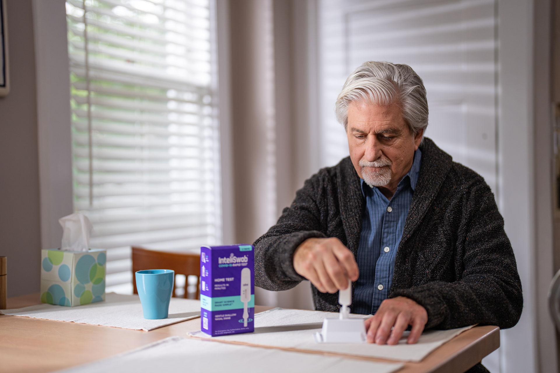 An older man uses InteliSwab.