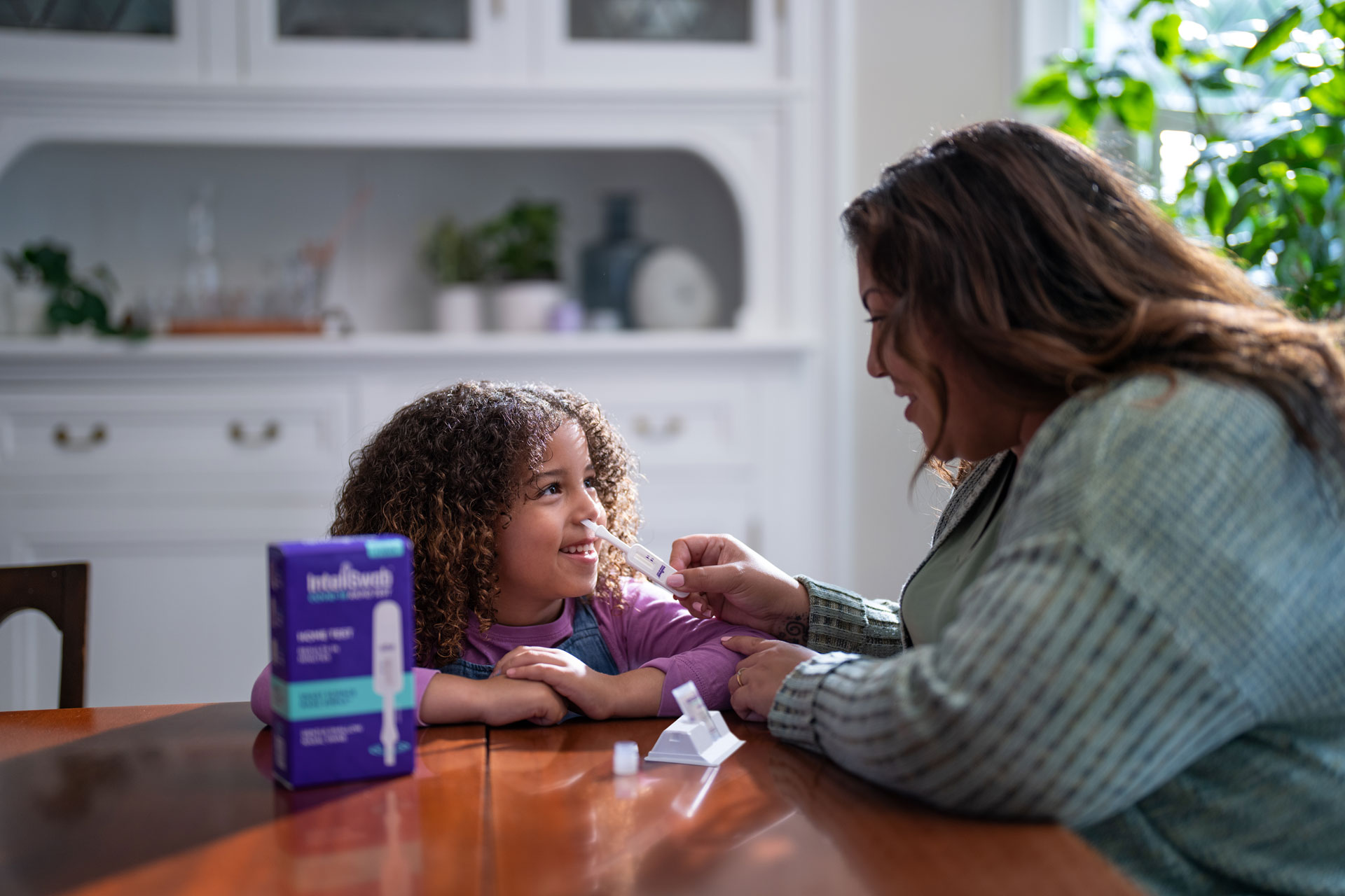A mother swabs her daughter's nose.